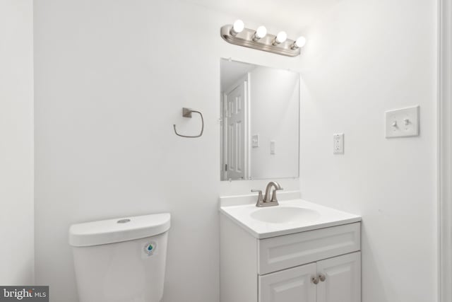 half bath featuring vanity and toilet