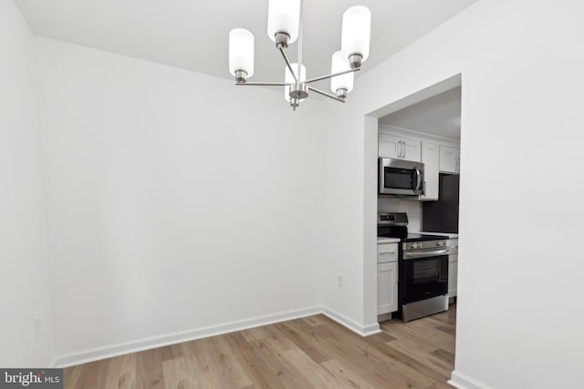 unfurnished dining area featuring a chandelier, light wood-style flooring, and baseboards