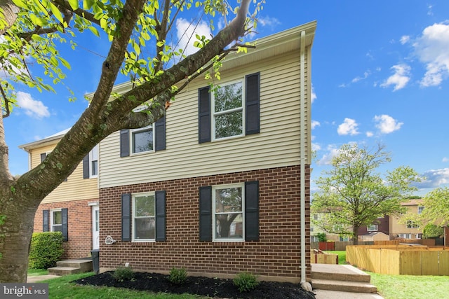 view of front of property with brick siding and fence