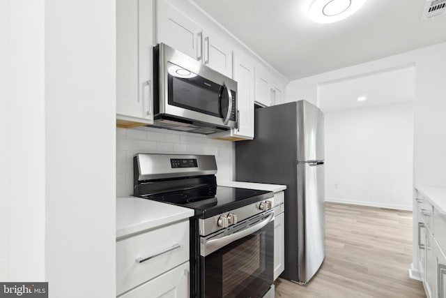 kitchen with appliances with stainless steel finishes, light countertops, backsplash, white cabinets, and light wood-style flooring