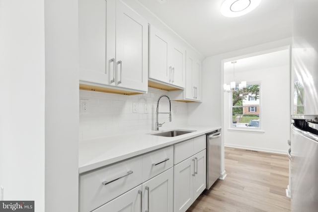 kitchen with a sink, dishwasher, light countertops, light wood-style flooring, and decorative backsplash
