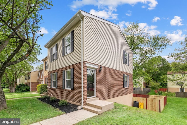 view of side of home featuring a lawn and brick siding