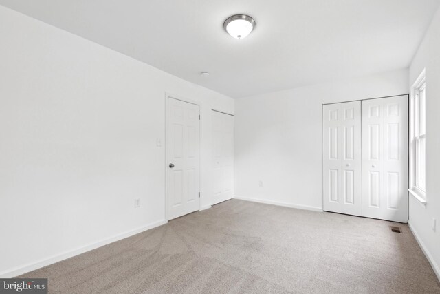 unfurnished bedroom with carpet, multiple closets, and baseboards