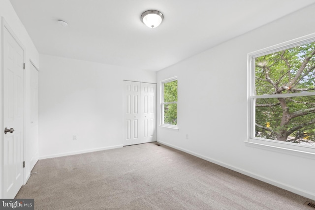 unfurnished room with plenty of natural light, carpet, and baseboards