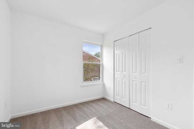 unfurnished bedroom with carpet, baseboards, and a closet