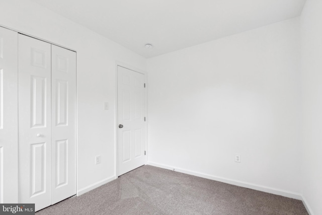 unfurnished bedroom with carpet, a closet, and baseboards