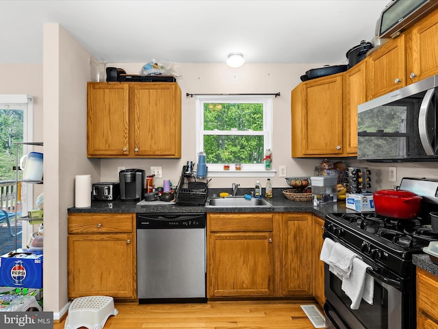 kitchen featuring a sink, appliances with stainless steel finishes, brown cabinets, and a wealth of natural light