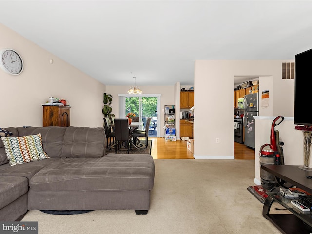 living area featuring baseboards, a chandelier, and light carpet