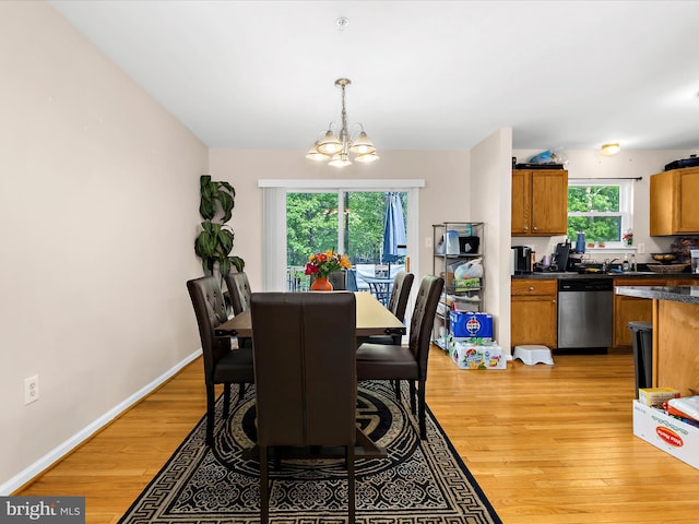 dining space featuring baseboards, light wood finished floors, and a chandelier