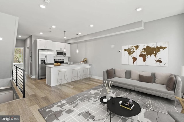 living area with light wood-style floors, baseboards, and recessed lighting