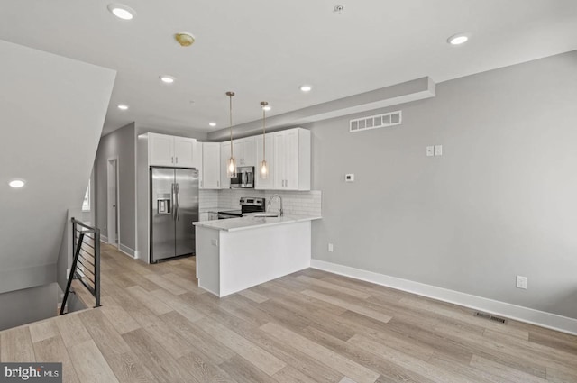 kitchen featuring visible vents, a sink, a peninsula, and stainless steel appliances