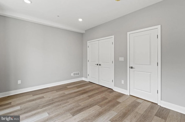 unfurnished bedroom featuring recessed lighting, baseboards, visible vents, and wood finished floors