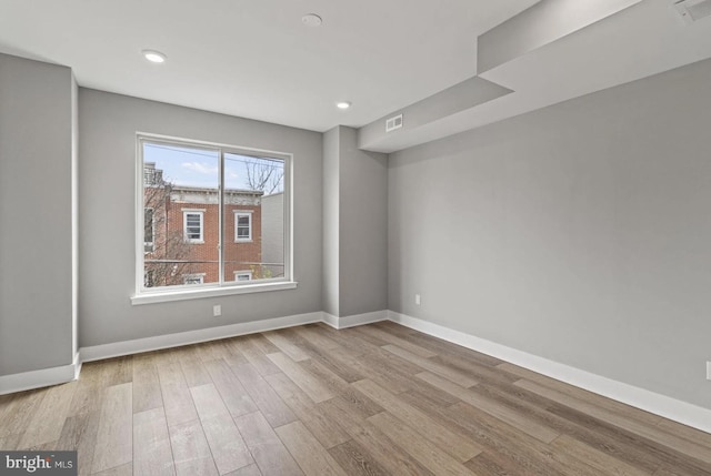 empty room with recessed lighting, baseboards, visible vents, and wood finished floors