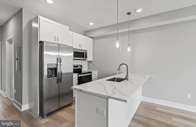 kitchen with a sink, white cabinets, a peninsula, light wood-style floors, and stainless steel appliances