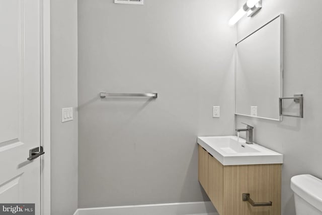 bathroom featuring vanity, baseboards, visible vents, and toilet