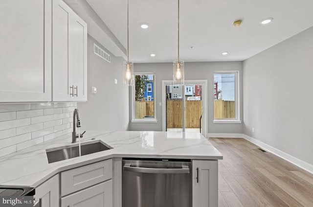 kitchen with visible vents, dishwasher, a sink, a peninsula, and light wood-style floors