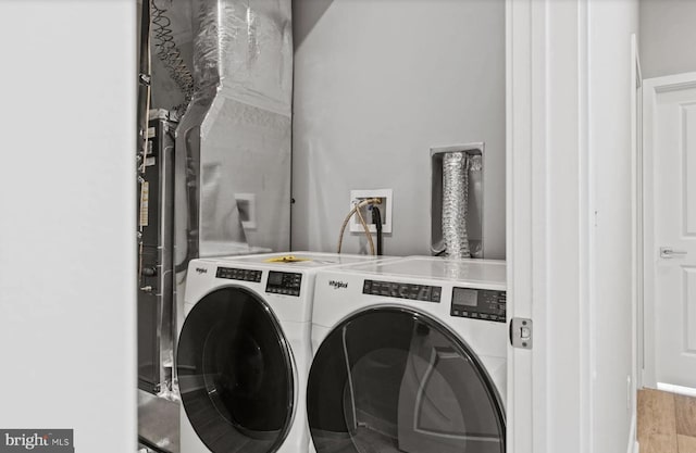 clothes washing area featuring laundry area, wood finished floors, and washing machine and clothes dryer