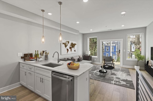 kitchen featuring a sink, stainless steel dishwasher, light wood-style flooring, and open floor plan