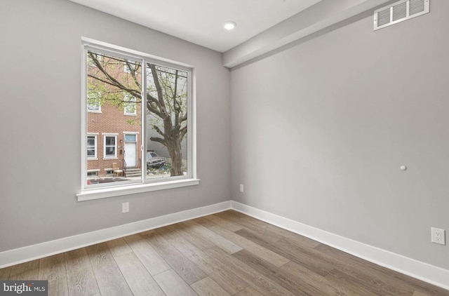 spare room with baseboards, recessed lighting, wood finished floors, and visible vents