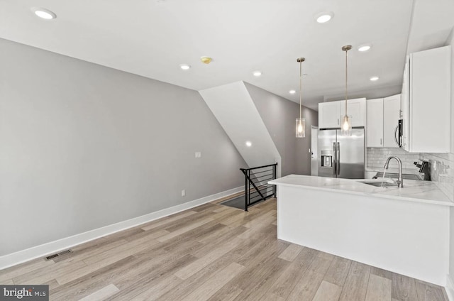 kitchen with light wood-style flooring, appliances with stainless steel finishes, backsplash, and white cabinets