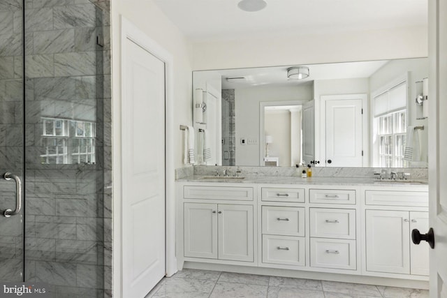 bathroom with a sink, a shower stall, double vanity, and marble finish floor