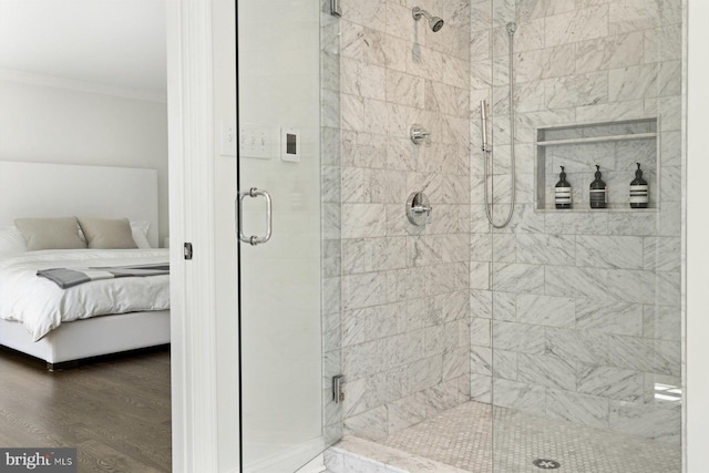 ensuite bathroom featuring crown molding, wood finished floors, connected bathroom, and a stall shower