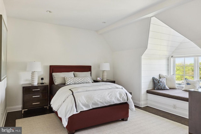 bedroom featuring baseboards, vaulted ceiling with beams, and wood finished floors