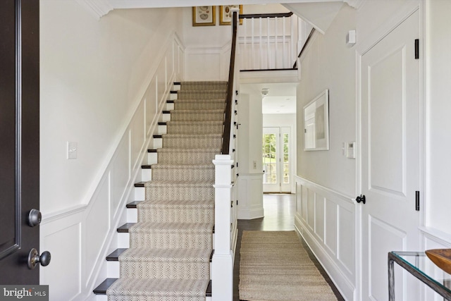 stairway featuring a wainscoted wall and a decorative wall