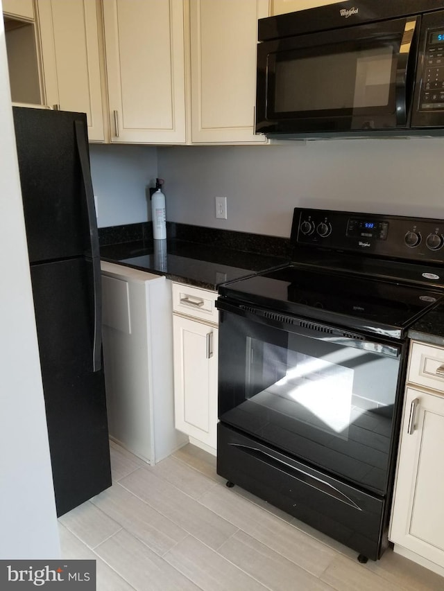 kitchen featuring light wood-style flooring, black appliances, dark stone countertops, and white cabinetry
