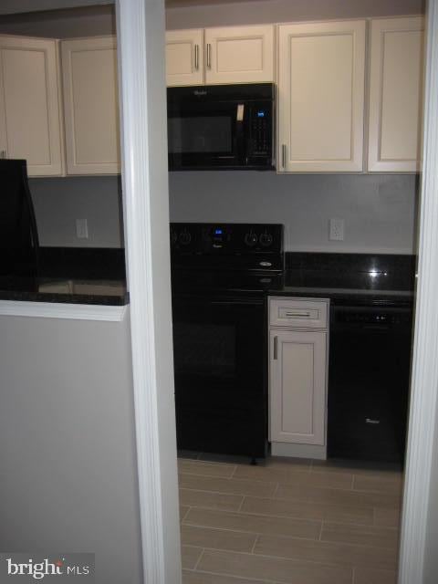 kitchen with white cabinetry, black appliances, and dark countertops
