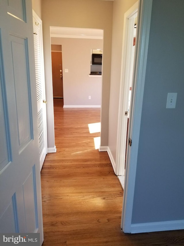 hall with baseboards and light wood-type flooring