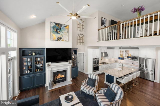 living room featuring dark wood-style flooring, a ceiling fan, high vaulted ceiling, and a high end fireplace