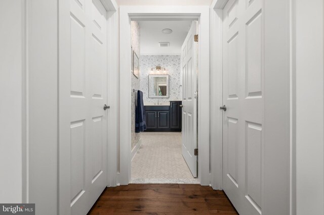 corridor featuring visible vents, dark wood-style floors, and wallpapered walls