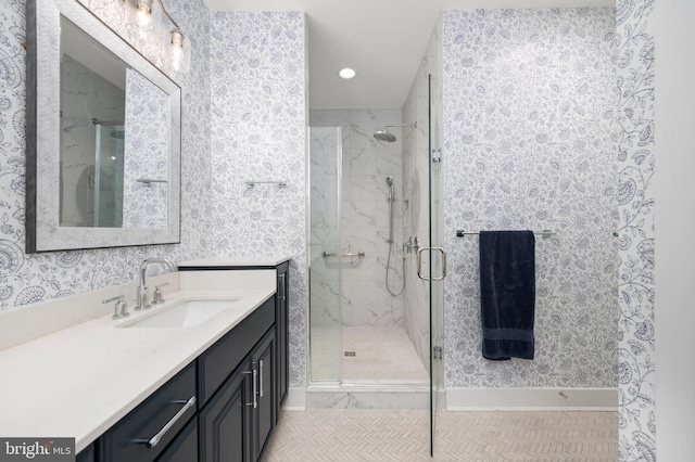 full bathroom featuring vanity, a marble finish shower, recessed lighting, baseboards, and wallpapered walls
