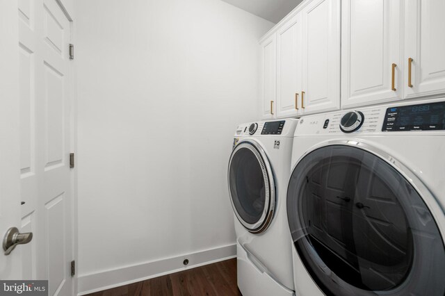 clothes washing area with cabinet space, baseboards, washer and clothes dryer, and dark wood-type flooring
