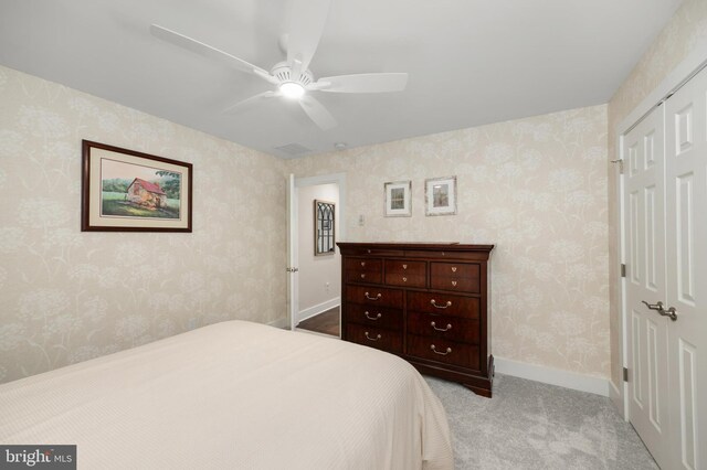 carpeted bedroom with baseboards, ceiling fan, a closet, and wallpapered walls