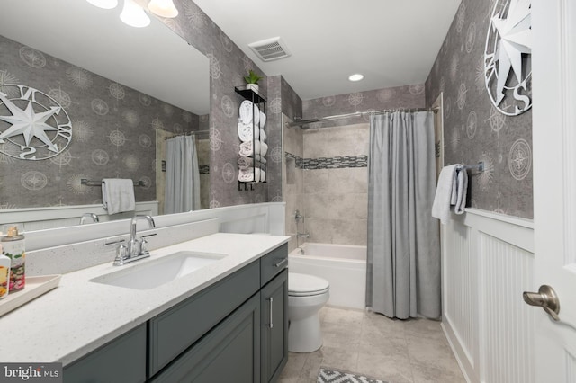 full bathroom with visible vents, shower / bath combo with shower curtain, vanity, toilet, and a wainscoted wall