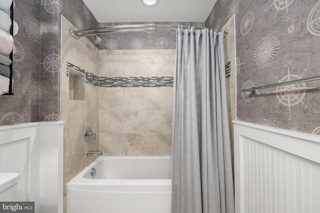 bathroom featuring toilet, wallpapered walls, and shower / tub combo
