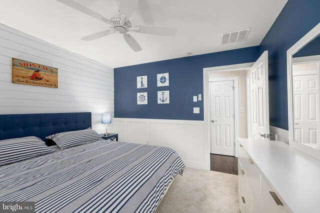 bedroom featuring visible vents, a ceiling fan, wainscoting, and carpet floors