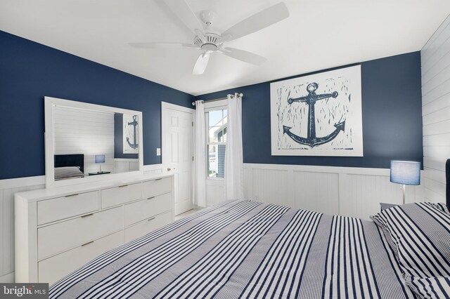 bedroom featuring a ceiling fan and wainscoting