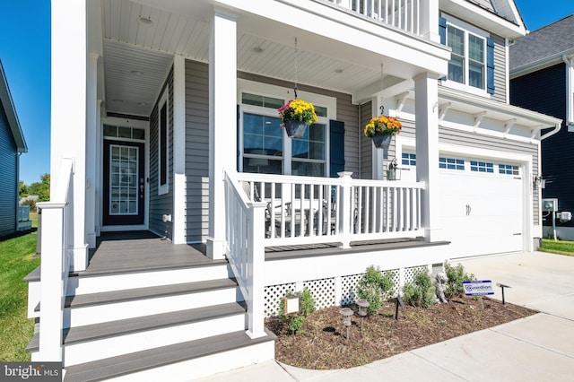 view of exterior entry featuring a porch, a garage, and concrete driveway