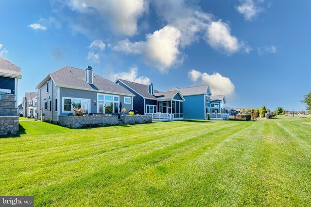 rear view of property featuring a yard and a sunroom