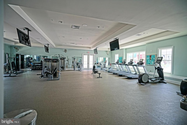 gym featuring a tray ceiling, visible vents, and french doors