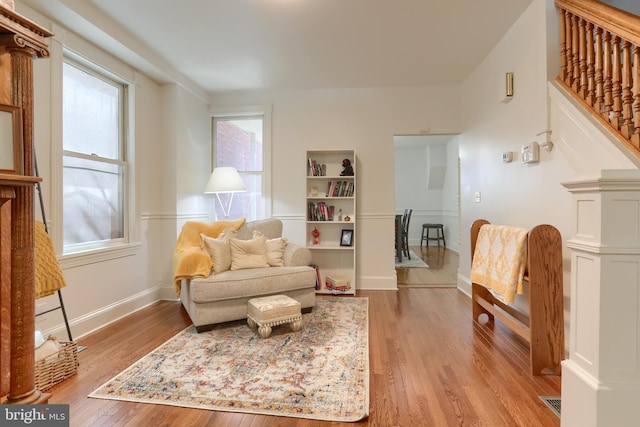 living area with light wood-type flooring, stairs, plenty of natural light, and baseboards