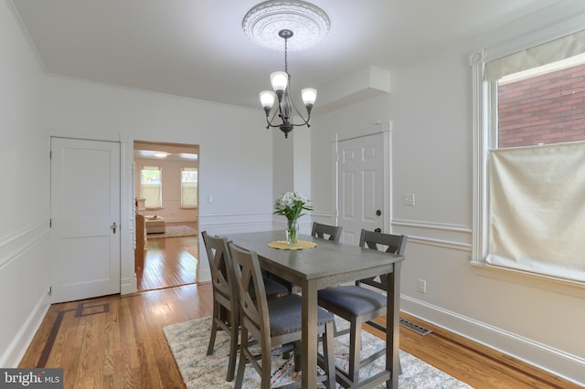 dining space featuring baseboards, light wood finished floors, and a notable chandelier