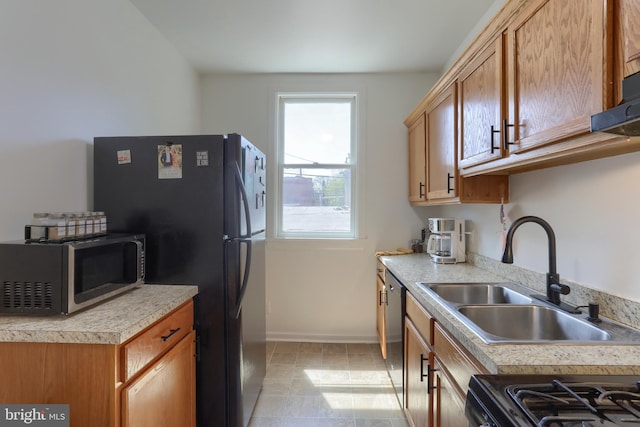 kitchen with a sink, baseboards, black appliances, and light countertops