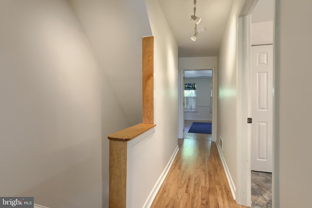 hallway featuring baseboards, an upstairs landing, track lighting, and light wood-style flooring