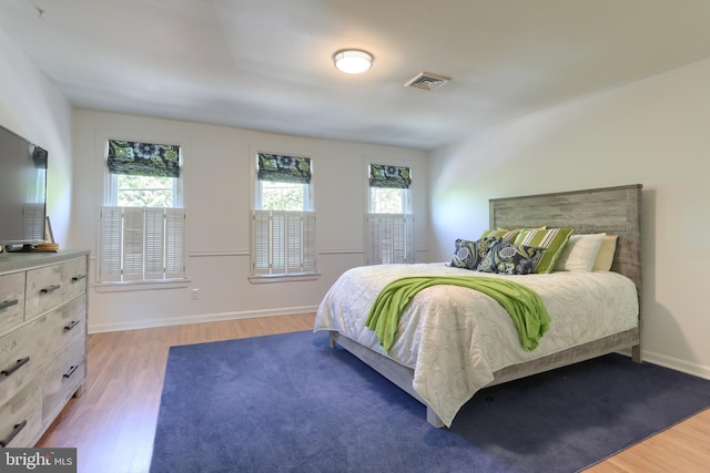 bedroom with light wood-style floors, multiple windows, and visible vents