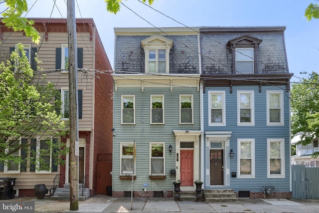 view of front facade with mansard roof, fence, and entry steps