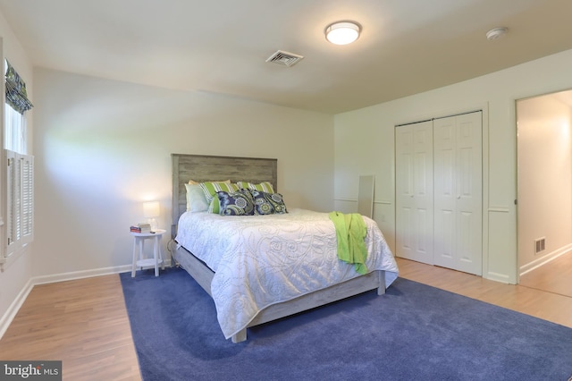 bedroom with visible vents, baseboards, wood finished floors, and a closet